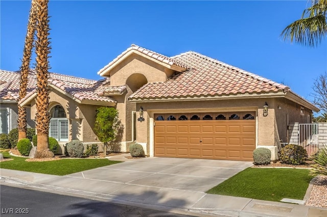 mediterranean / spanish-style home with stucco siding, a garage, driveway, and a tiled roof