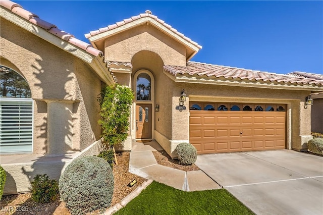 view of front facade featuring stucco siding, an attached garage, driveway, and a tiled roof