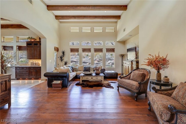 living room with beamed ceiling, a towering ceiling, and dark hardwood / wood-style flooring