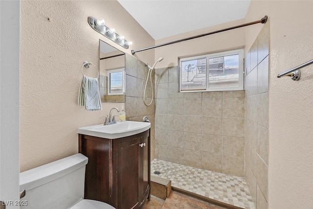 bathroom with vanity, tiled shower, and toilet