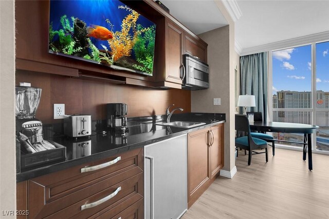 145 E Harmon Ave Unit 2603, Las Vegas, NV 89109 - kitchen featuring stainless steel microwave, a sink, light wood-style flooring, dark countertops, and crown molding