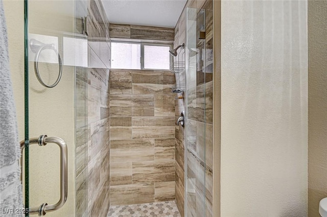 bathroom with a shower with shower door and toilet