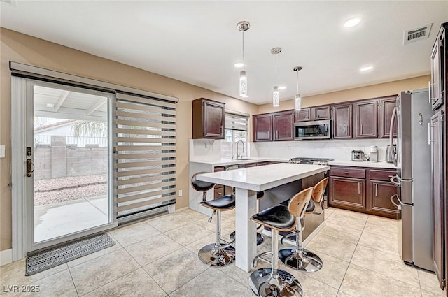 kitchen featuring light tile patterned flooring, sink, a center island, pendant lighting, and stainless steel appliances