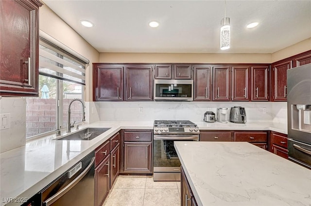 kitchen featuring pendant lighting, tasteful backsplash, sink, light tile patterned floors, and stainless steel appliances