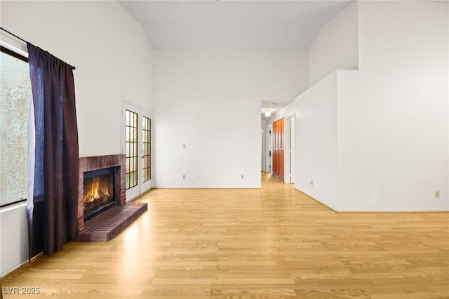 living room featuring a towering ceiling, a fireplace, and light hardwood / wood-style floors