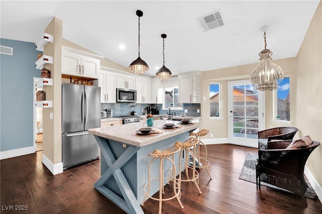 kitchen featuring visible vents, white cabinetry, light countertops, appliances with stainless steel finishes, and pendant lighting