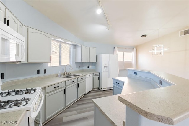 kitchen featuring lofted ceiling, white appliances, a sink, visible vents, and decorative light fixtures