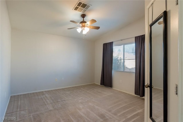 unfurnished room with visible vents, light carpet, vaulted ceiling, ceiling fan, and baseboards