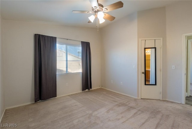 spare room featuring light carpet, vaulted ceiling, and a ceiling fan