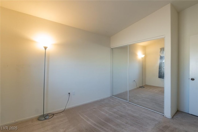 unfurnished bedroom featuring lofted ceiling, a closet, and carpet flooring