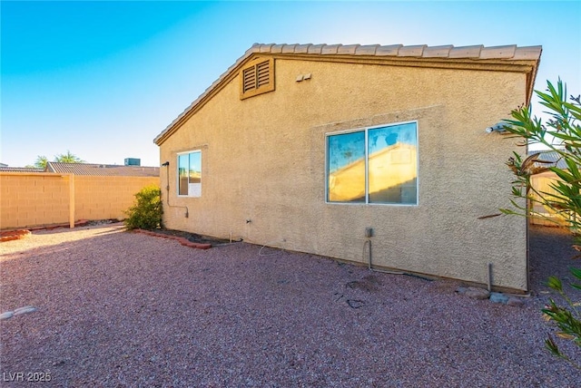 view of side of home with fence and stucco siding