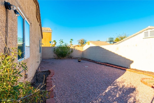 view of yard with a fenced backyard and central AC unit