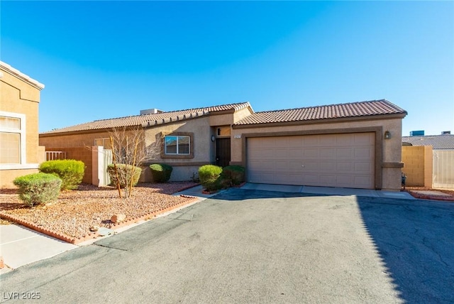 mediterranean / spanish home with a tile roof, driveway, an attached garage, and stucco siding