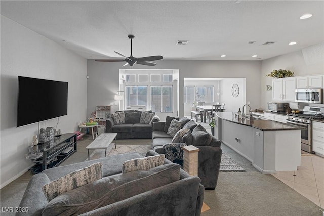 living room with sink, light colored carpet, and ceiling fan