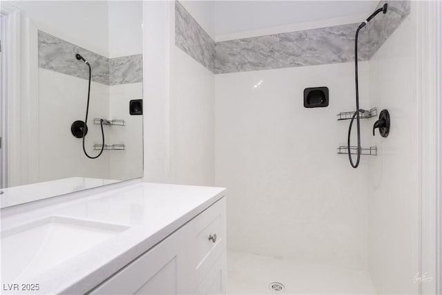 bathroom featuring tiled shower and vanity