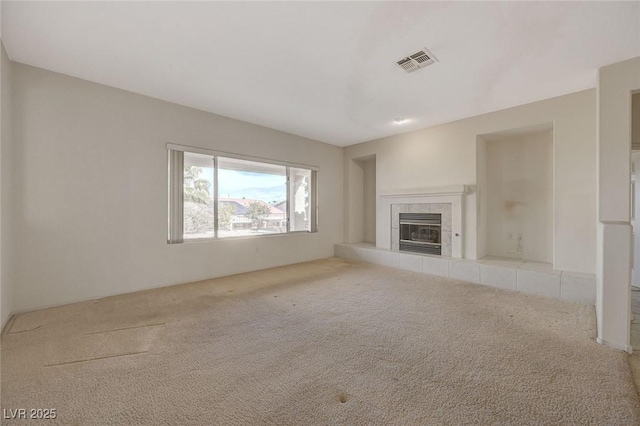 unfurnished living room featuring light colored carpet and a tiled fireplace