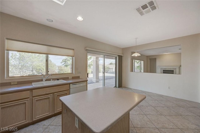 kitchen featuring a kitchen island, a fireplace, decorative light fixtures, sink, and white dishwasher