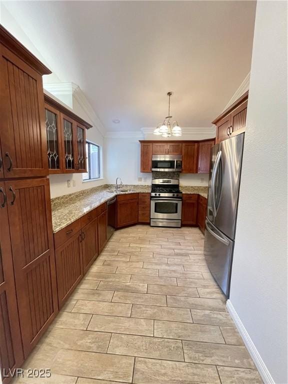 kitchen featuring light stone counters, hanging light fixtures, ornamental molding, and stainless steel appliances