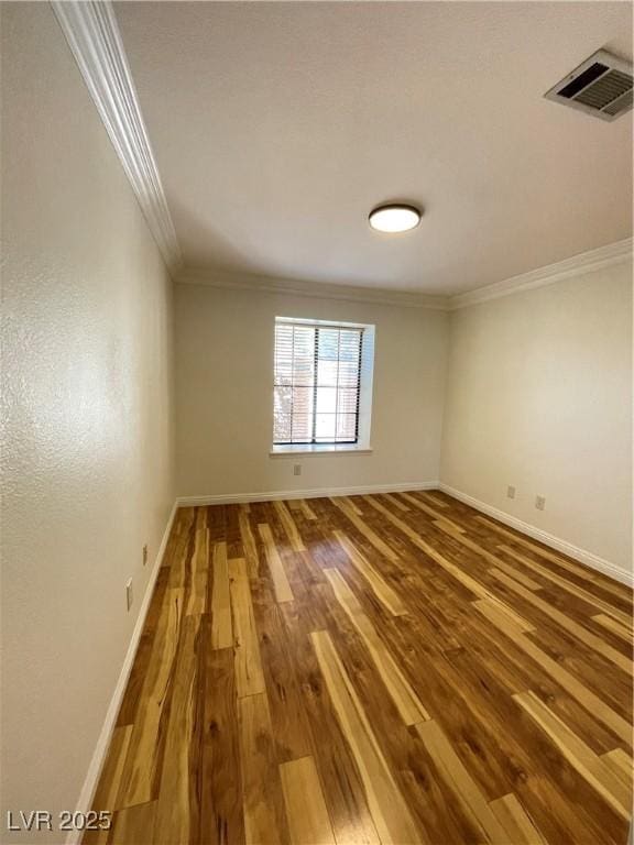 spare room featuring hardwood / wood-style flooring and ornamental molding