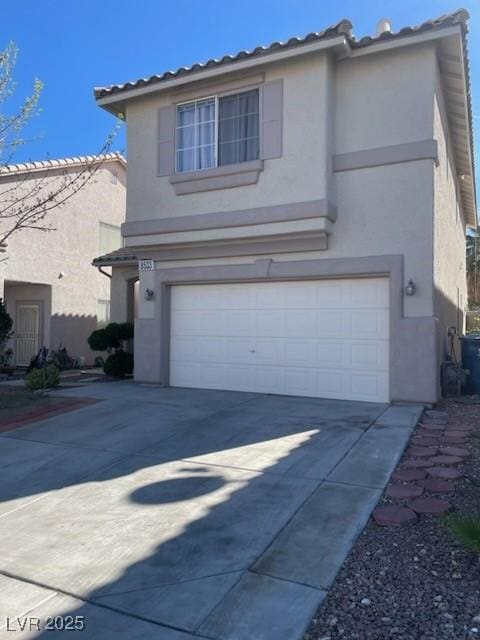 view of front of home with concrete driveway, a tile roof, an attached garage, and stucco siding