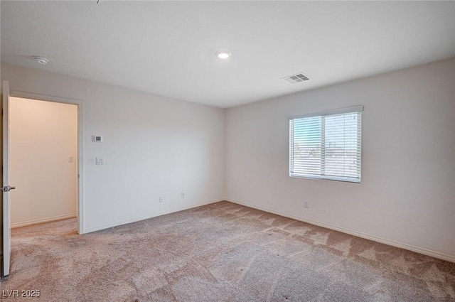 unfurnished room with light carpet, visible vents, and baseboards