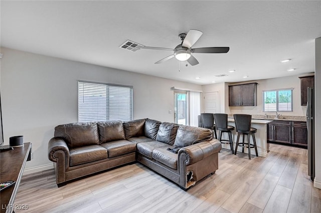 living area with recessed lighting, visible vents, light wood-style flooring, a ceiling fan, and baseboards