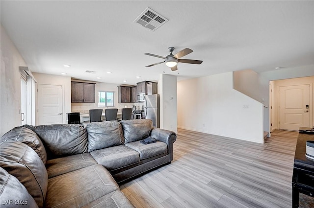 living room featuring light wood-style flooring, recessed lighting, a ceiling fan, visible vents, and baseboards