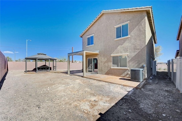 rear view of property with a patio, a fenced backyard, central air condition unit, a gazebo, and stucco siding