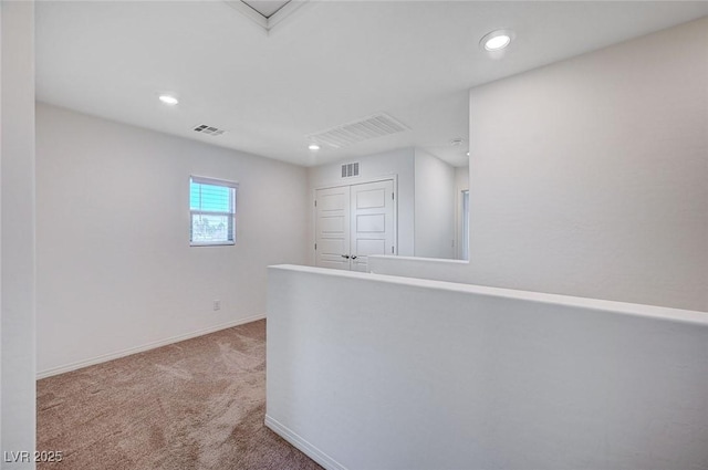 corridor featuring light carpet, recessed lighting, visible vents, and baseboards