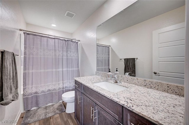 bathroom featuring curtained shower, toilet, wood finished floors, vanity, and visible vents