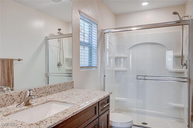 bathroom with toilet, a shower stall, and vanity