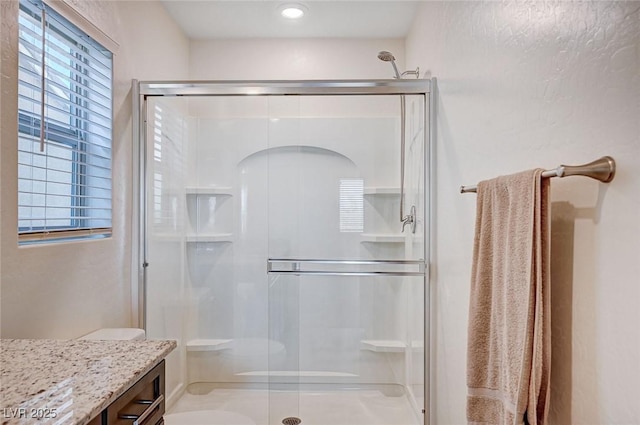 full bath featuring plenty of natural light, a shower stall, and vanity