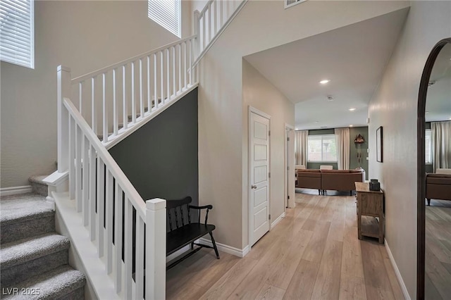 stairway with recessed lighting, a towering ceiling, baseboards, and wood finished floors