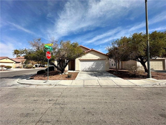 view of front of house featuring a garage, driveway, a tile roof, and stucco siding