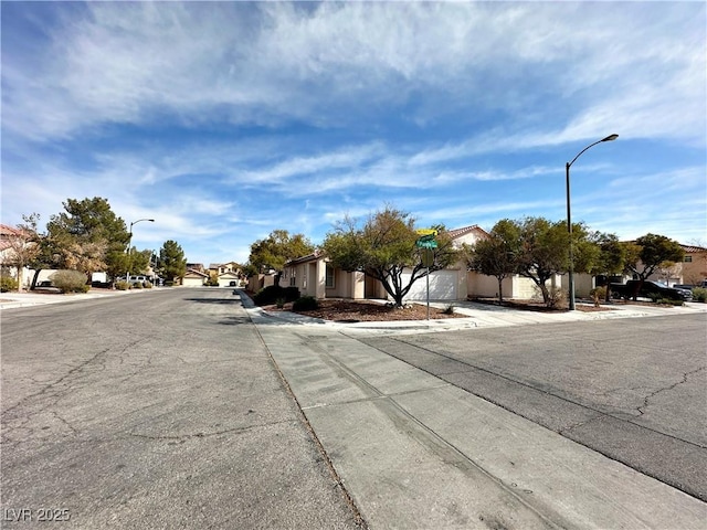 11036 Parete Ct, Las Vegas, NV 89141 - view of asphalt road with sidewalks, a residential view, street lights, and curbs