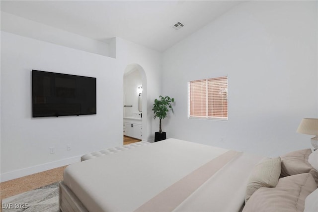 carpeted bedroom featuring connected bathroom and vaulted ceiling