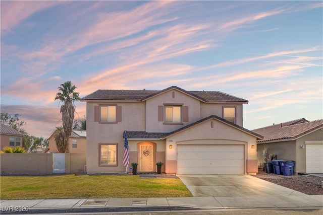 traditional-style house featuring fence, an attached garage, stucco siding, concrete driveway, and a lawn