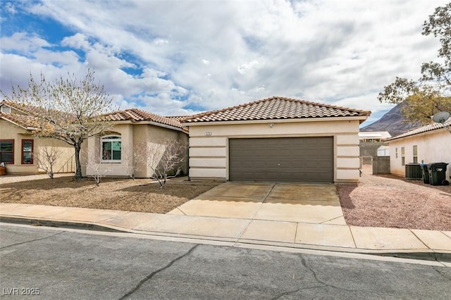 mediterranean / spanish-style home featuring cooling unit, a garage, driveway, and stucco siding