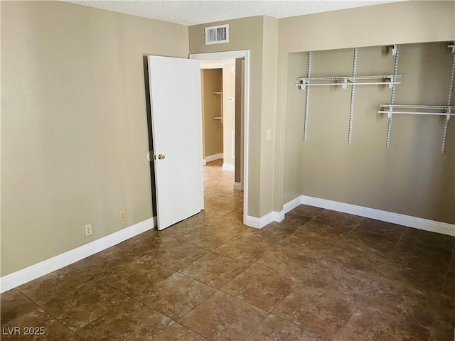 unfurnished bedroom featuring a textured ceiling, a closet, visible vents, and baseboards