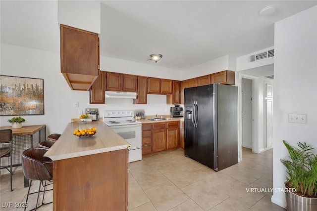 kitchen featuring sink, white electric range, a kitchen bar, black fridge with ice dispenser, and kitchen peninsula