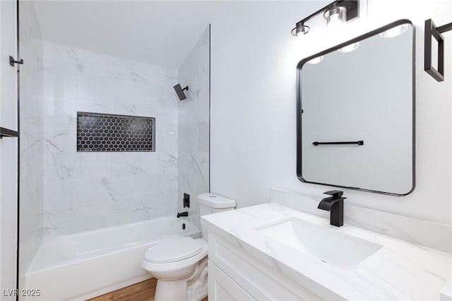 full bathroom featuring hardwood / wood-style flooring, tiled shower / bath, vanity, and toilet