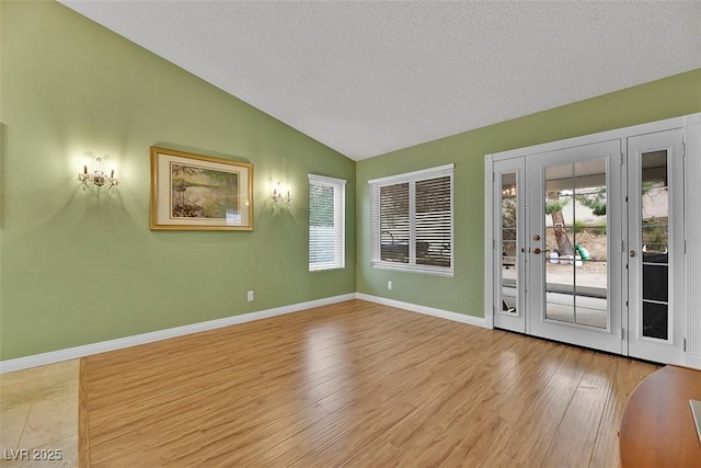 interior space with vaulted ceiling, a textured ceiling, and light hardwood / wood-style flooring