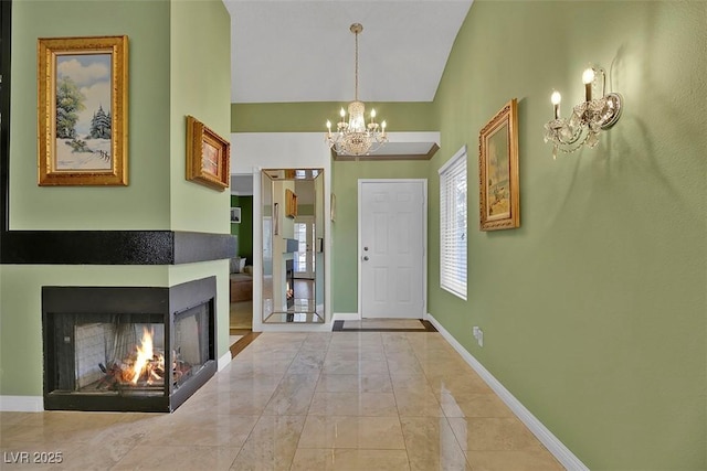 foyer with a multi sided fireplace, lofted ceiling, and a notable chandelier