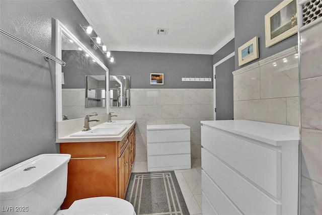 bathroom with ornamental molding, a bathing tub, tile walls, and vanity