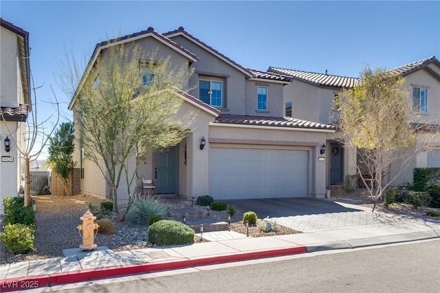 view of front facade featuring driveway, a tiled roof, an attached garage, and stucco siding