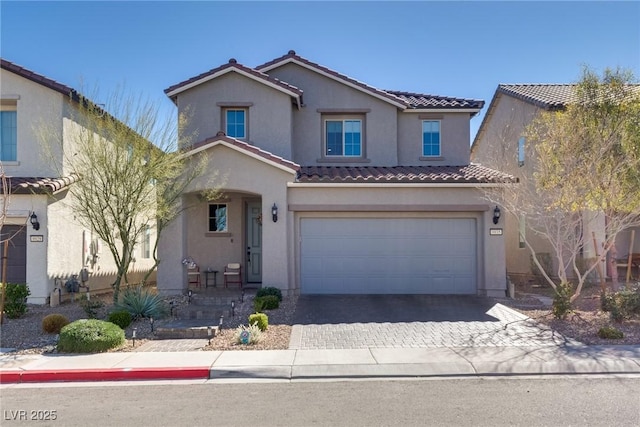 view of front of property featuring a garage, decorative driveway, a tiled roof, and stucco siding