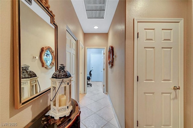 corridor featuring visible vents, baseboards, and light tile patterned flooring