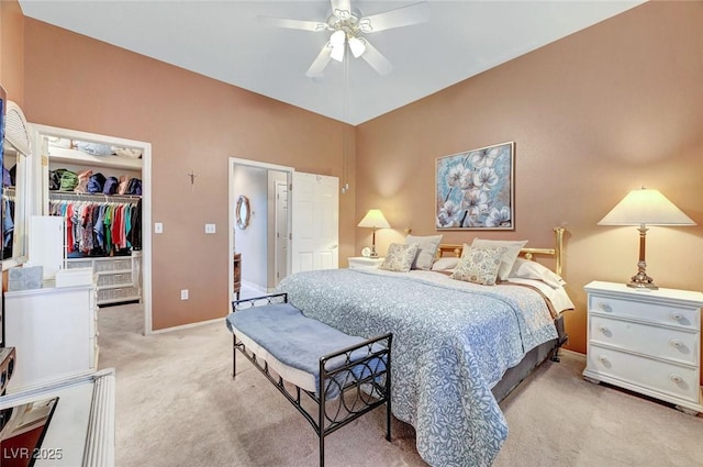 bedroom featuring a ceiling fan, a walk in closet, a closet, and light carpet