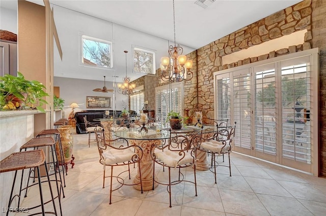 dining room featuring light tile patterned floors, a fireplace, a chandelier, and a towering ceiling