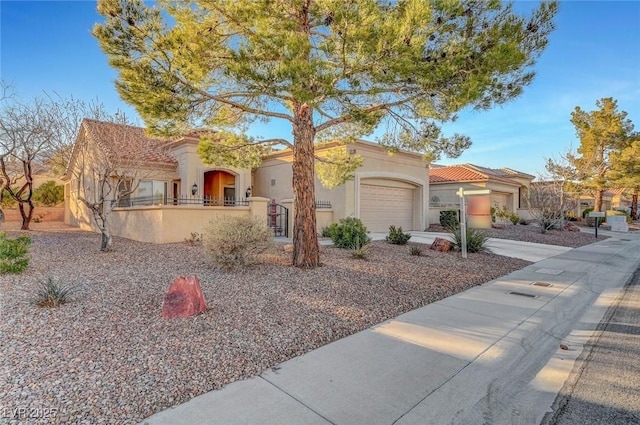 mediterranean / spanish-style home featuring an attached garage, a tiled roof, concrete driveway, and stucco siding